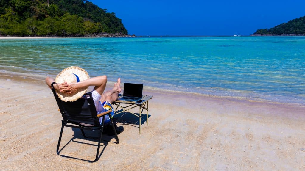 Nomaddigitalwithlaptopandrunningremotelywithbrightscenicviewnearpoolsideonthebeachinsummertime2