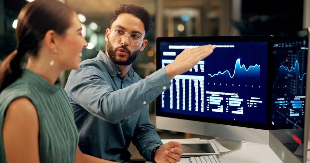 Businesspeoplestockmarketandnightwithcomputerforprofitfinancialgrowthorincreaseatofficebusinessmanwomanorbrokerswithtechscreenordisplayforonlinetradingorinvestment