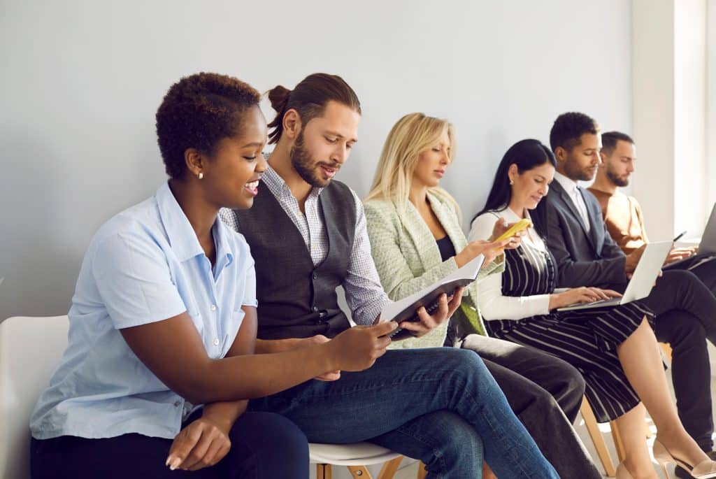 Multiracialpeoplewaitinlineforinterviewinoffice